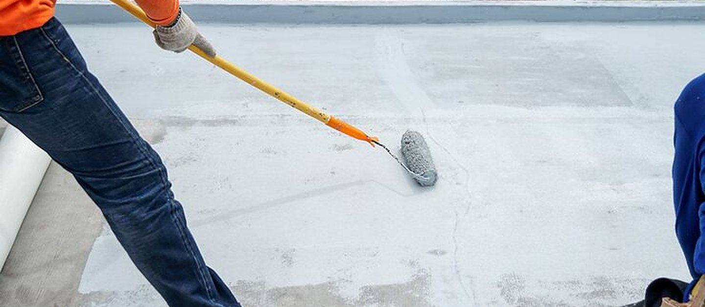 Zeb Builders crew applying reinforcing mesh and grey waterproof membrane across a flat roof